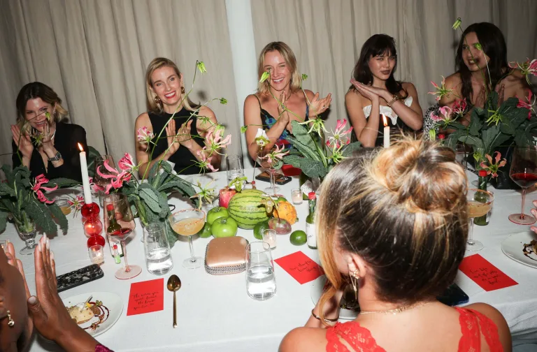 Image of a Sakara event, showcasing a dining table full of produce, menus, and drinks surrounded by Sakara co-founders and influencers.