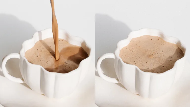 Two white mugs filled with frothy cinnamon mocha latte, one mid-pour.