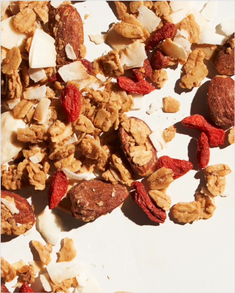 Sakara Classic Superfood Granola close-up showing toasted oats, whole almonds, coconut chips, and dried goji berries.