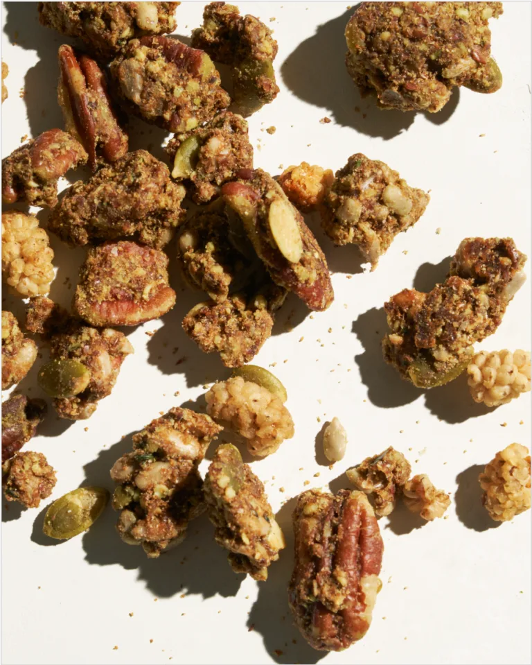 Sakara Plant Protein Granola close-up showing pecans, mulberries, pumpkin seeds, and matcha-coated granola clusters.