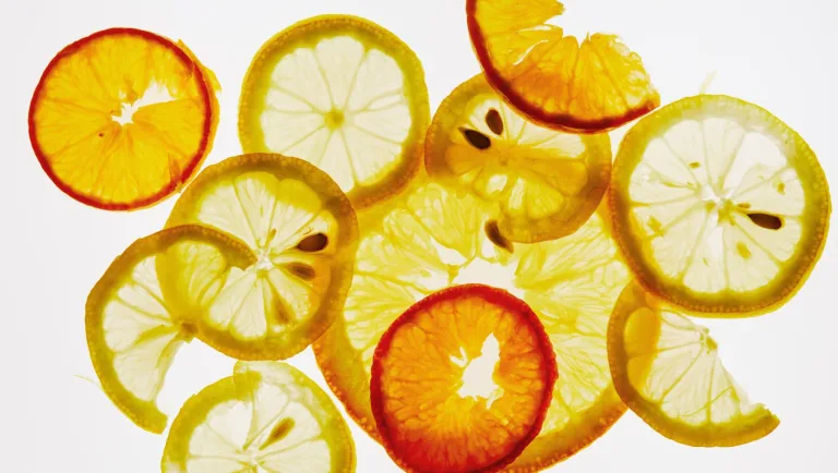 Backlit slices of citrus including lemon and orange arranged in overlapping layers.