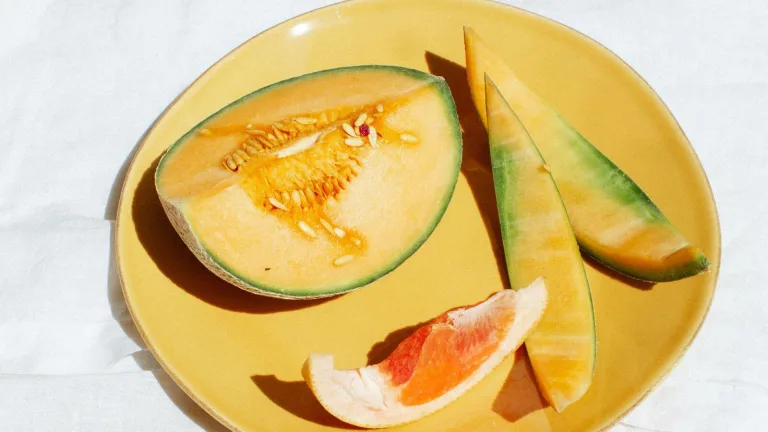 Sliced cantaloupe and grapefruit on a yellow plate.