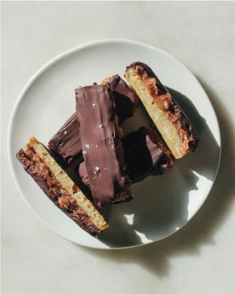 Stack of Metabolism Super Powder chocolate-coated cookie bars arranged on a white plate.