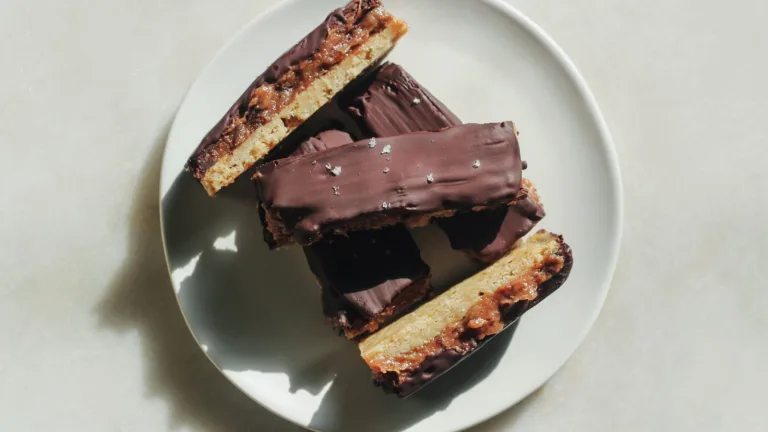 Stack of Metabolism Super Powder chocolate-coated cookie bars arranged on a white plate.