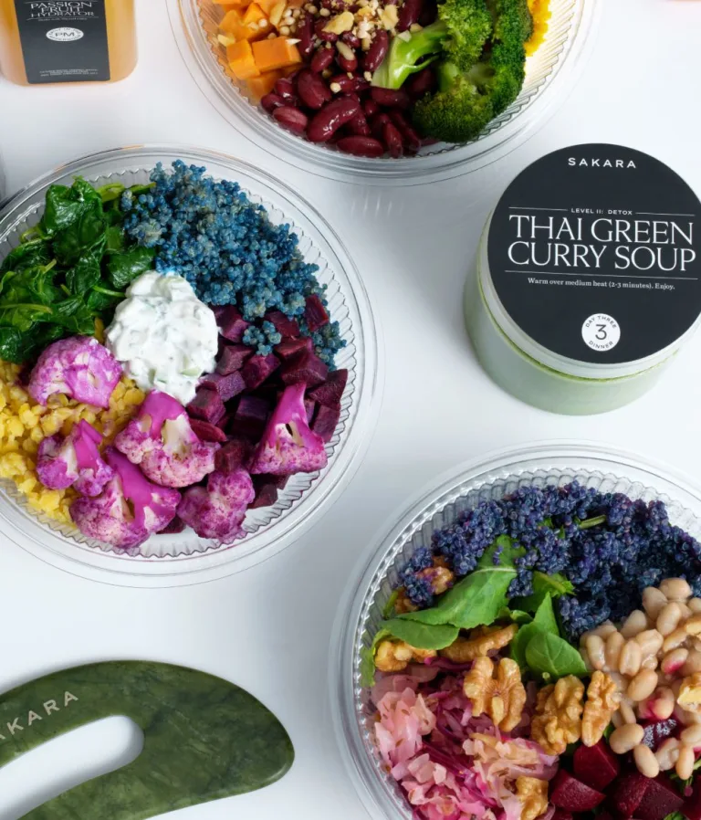 Sakara Level II: Detox ready-to-eat meals in clear round containers featuring pink cauliflower, blue quinoa, beets, leafy greens, beans, walnuts, and Thai Green Curry Soup.