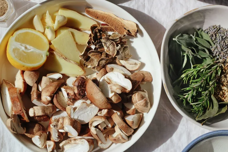 Assorted mushrooms and seaweed arranged on white plates with herbs and lemon nearby.