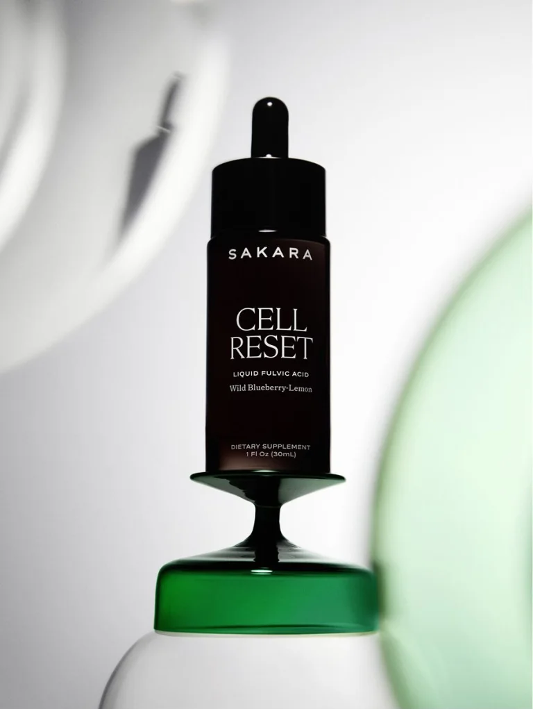 Sakara Cell Reset in a dark dropper bottle with black cap displayed on a green glass pedestal.