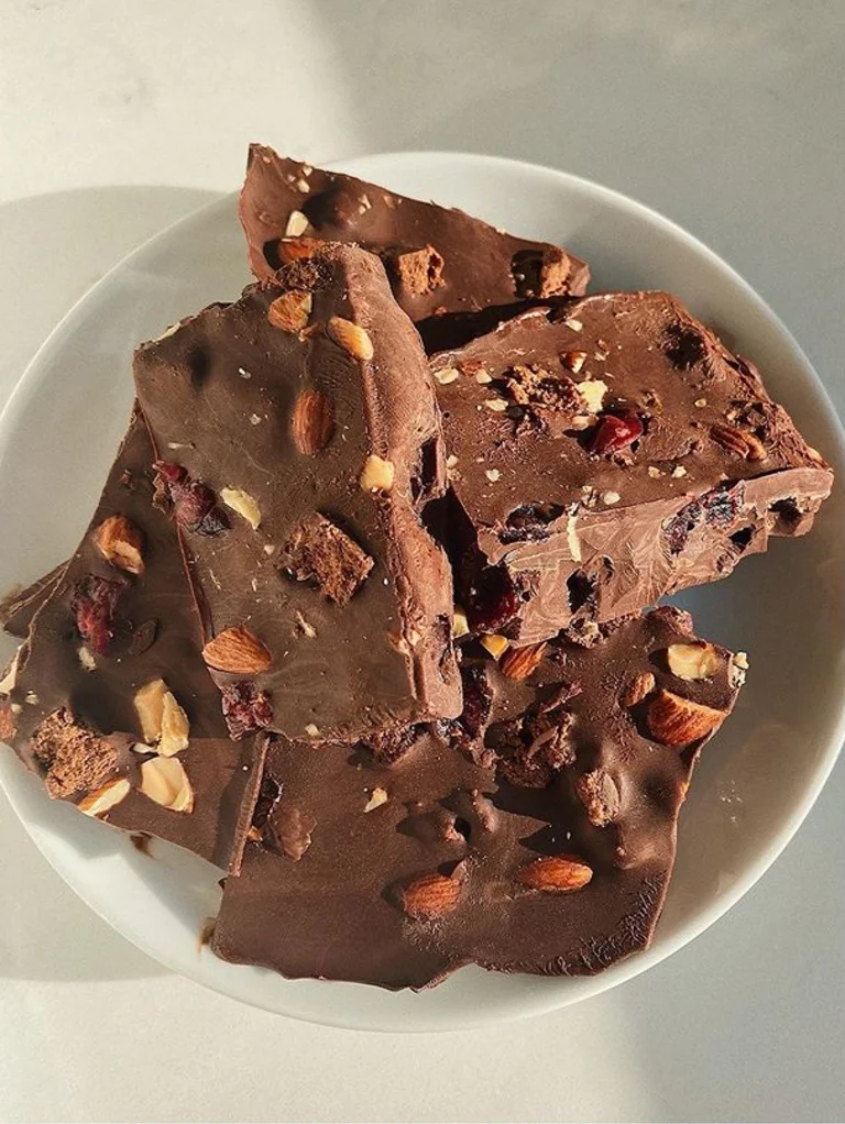 Sakara Metabolism Super Powder baked into chocolate bark with nuts on a plate, demonstrating baking it into a treat.