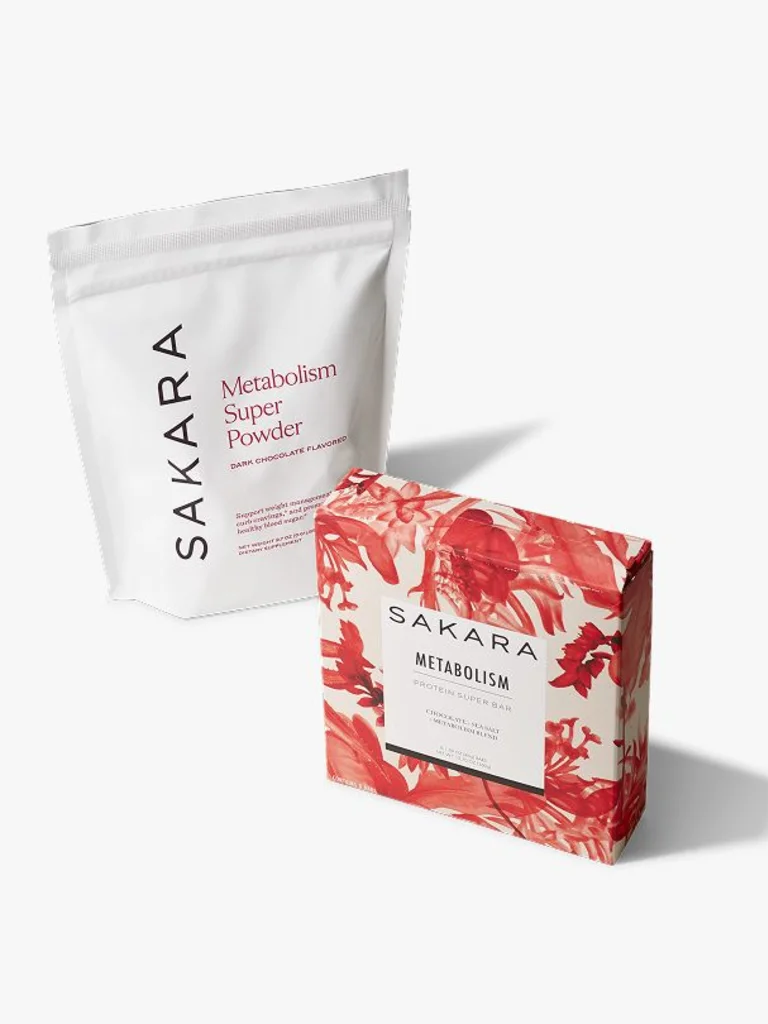 Sakara Metabolism Duo featuring Metabolism Super Powder in a white pouch and Metabolism Protein Super Bar in red floral packaging, sat next to each other on a grey background.