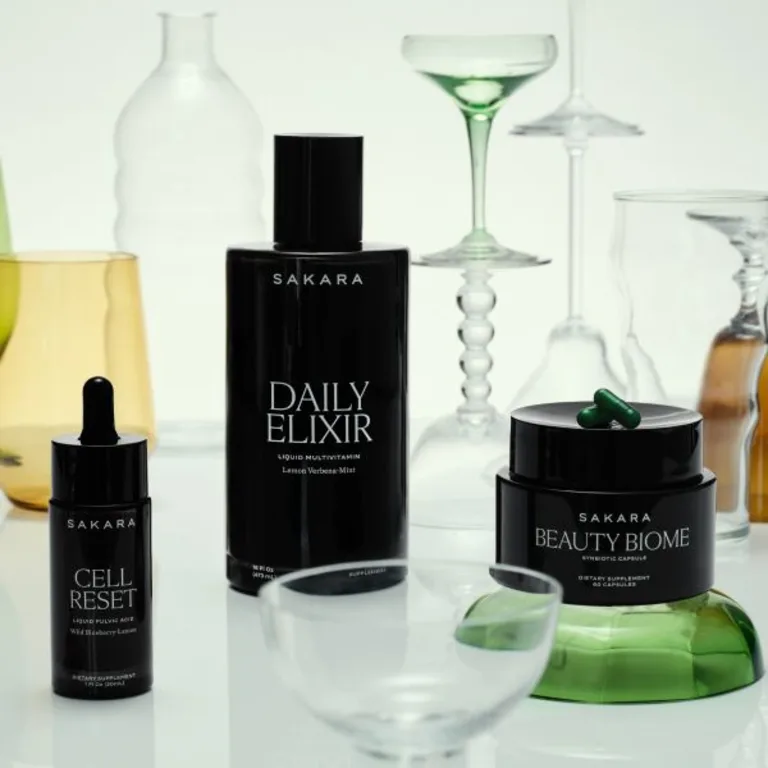 Sakara Skin Fundamentals Bundle with Daily Elixir, Cell Reset, and Beauty Biome supplements displayed with glassware and capsules.