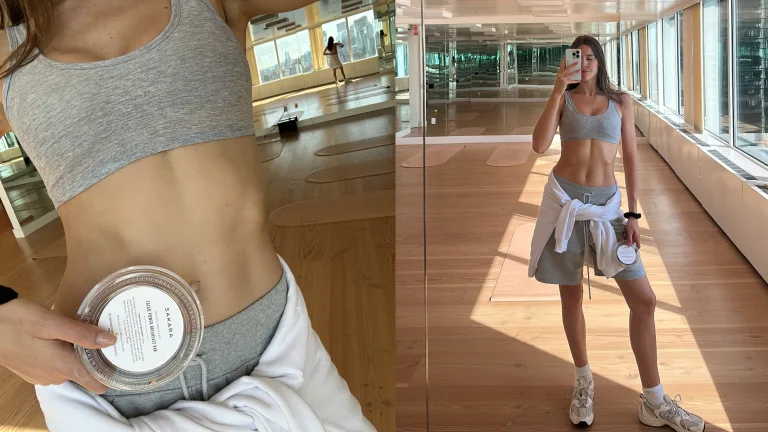 Kayla Principato in athletic wear taking a mirror selfie in a bright studio space.