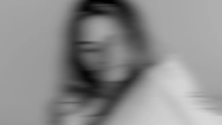 Blurred black-and-white portrait of a woman against a neutral background.